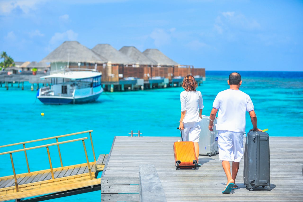 Home A couple arriving at a luxurious Maldives resort dock with luggage, capturing a tropical vacation vibe.