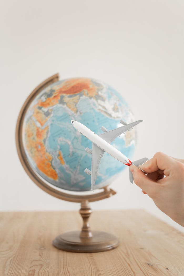 Mastering the First Impression: Your intriguing post title goes here Close-up of a hand with a toy airplane in front of a globe, symbolizing travel and exploration.